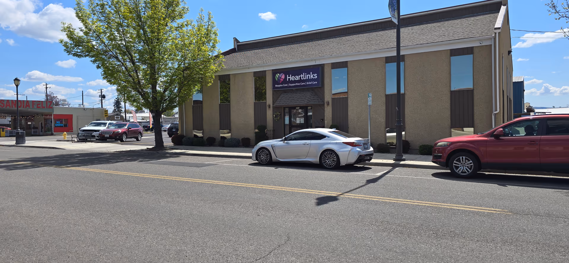 Exterior view of a Heartlinks senior living facility along a sunny street with parked cars.