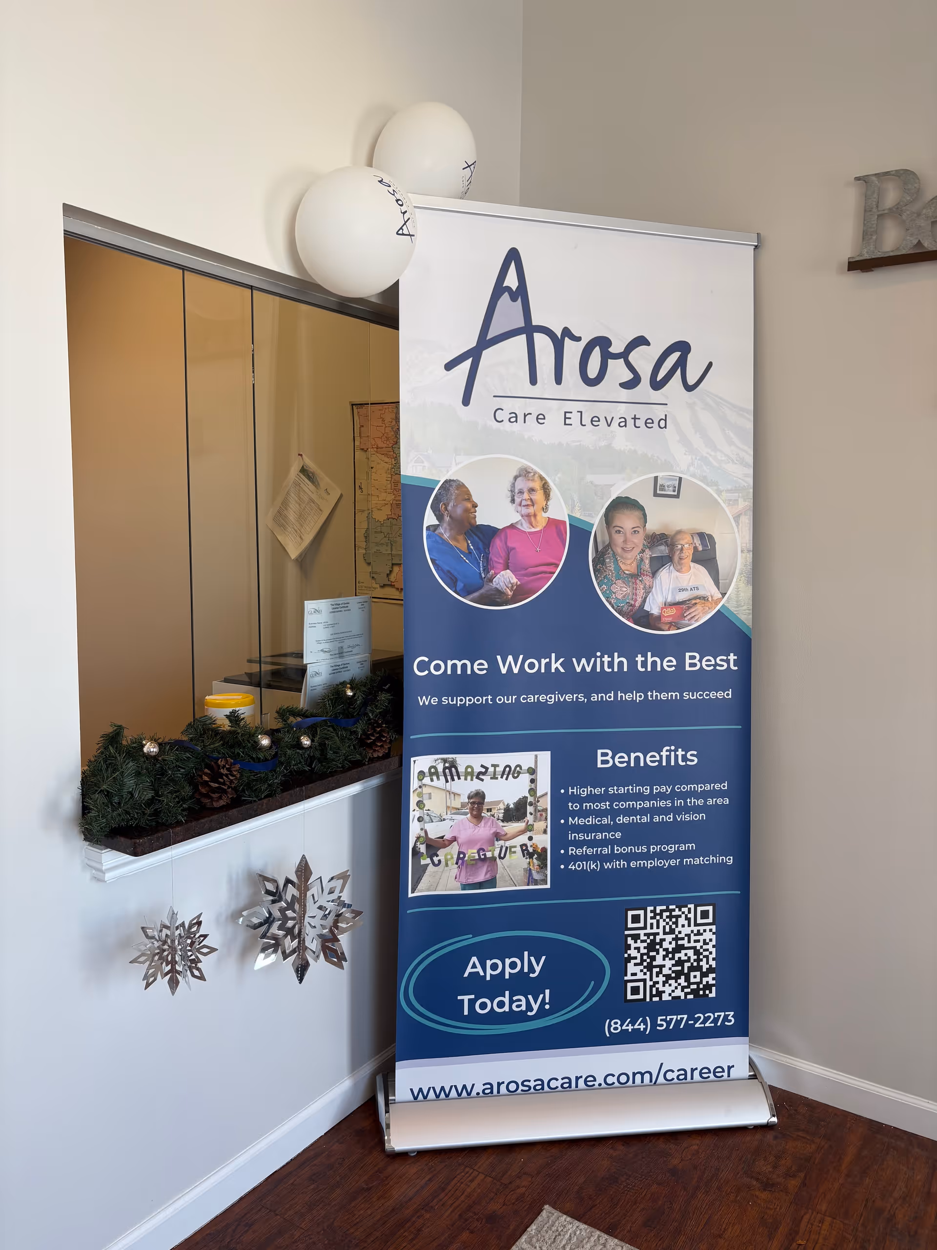 Indoor lobby corner with Arosa banner, balloons, garland, and snowflake decorations.