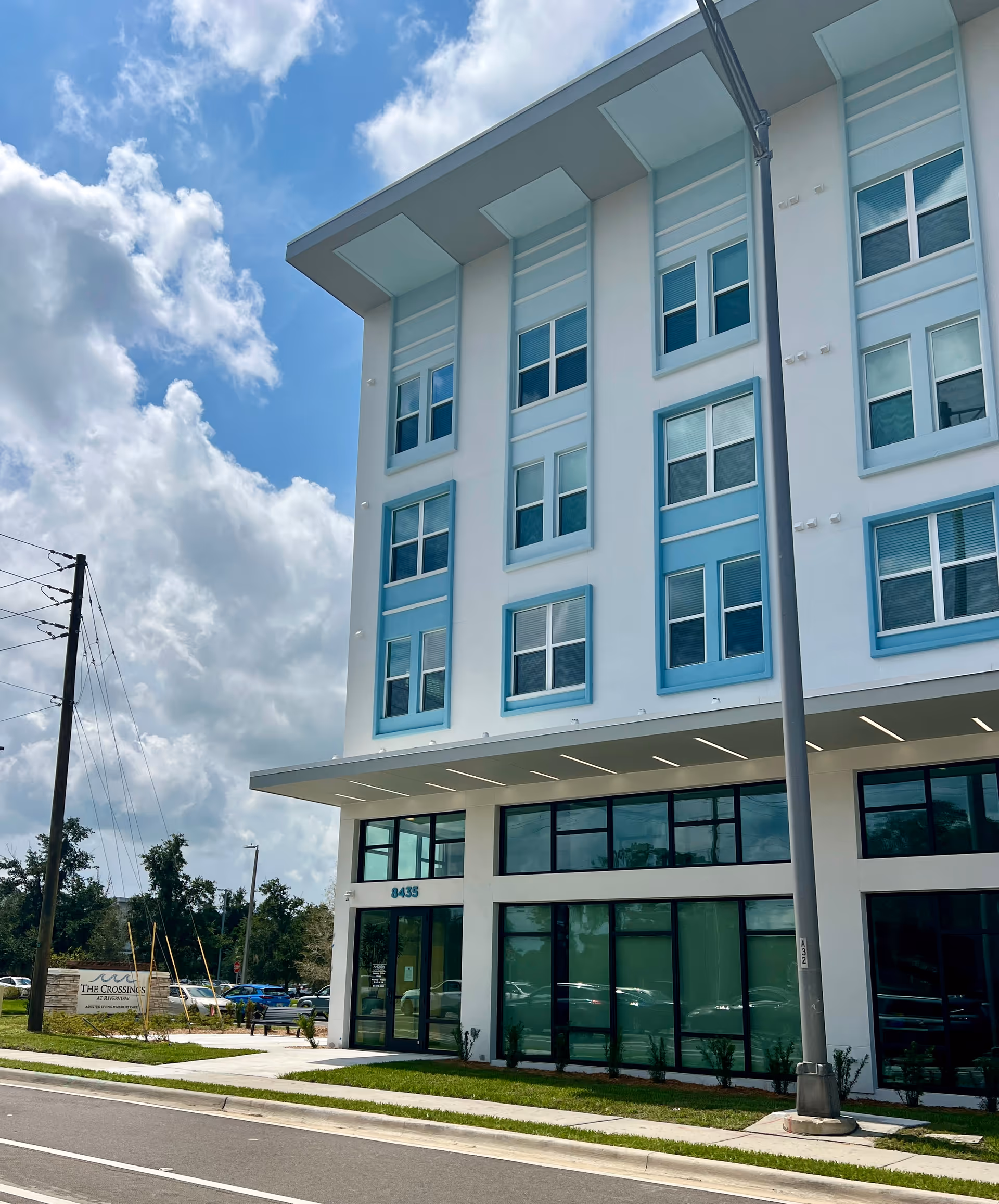 Modern senior living building exterior with glass entrance and blue-trimmed windows.