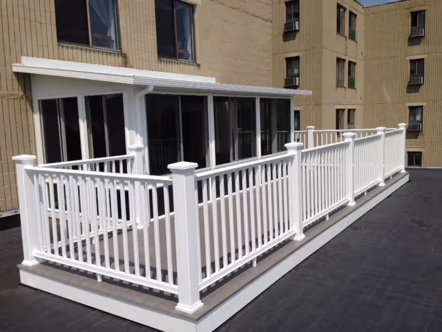 White railing balcony on a beige brick building exterior with sliding glass doors.
