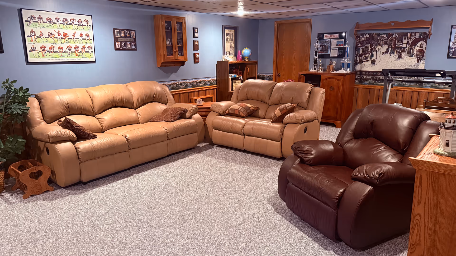 Cozy common living room with tan leather sofas, a brown recliner, and wall décor.
