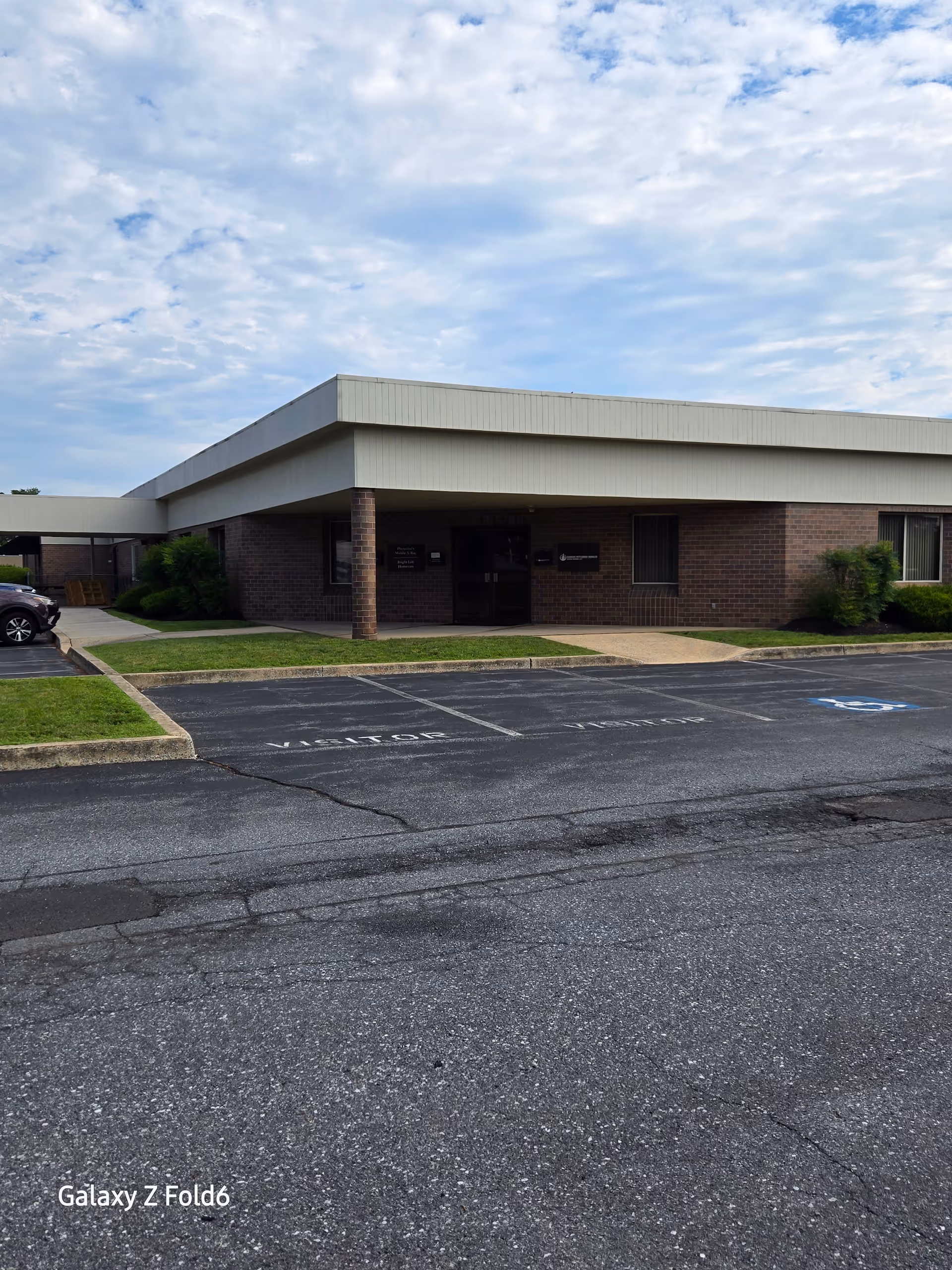 Exterior view of a brick senior care facility with a covered entrance and parking.