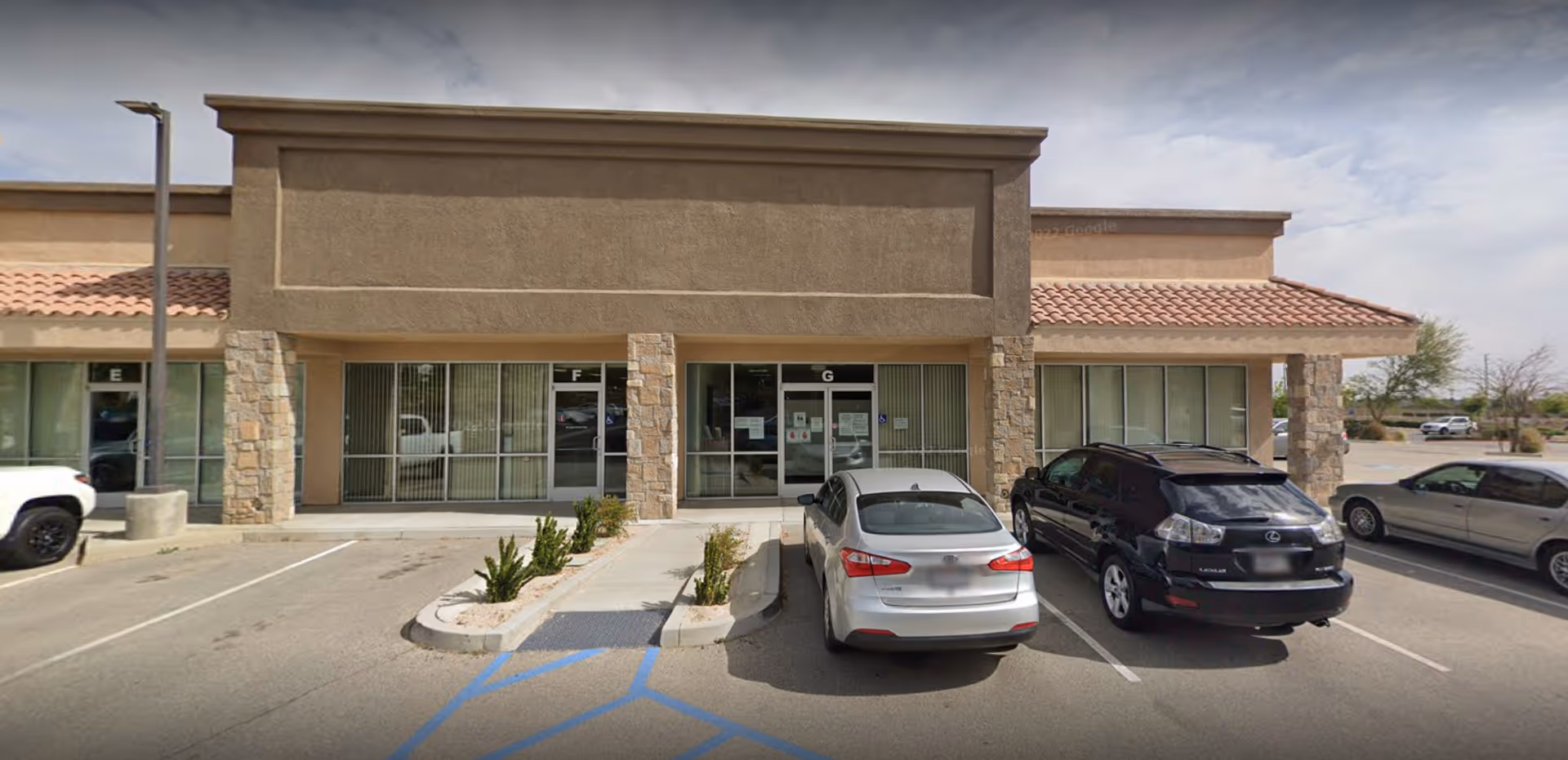 Front view of a beige, single-story hospice building with parked cars.