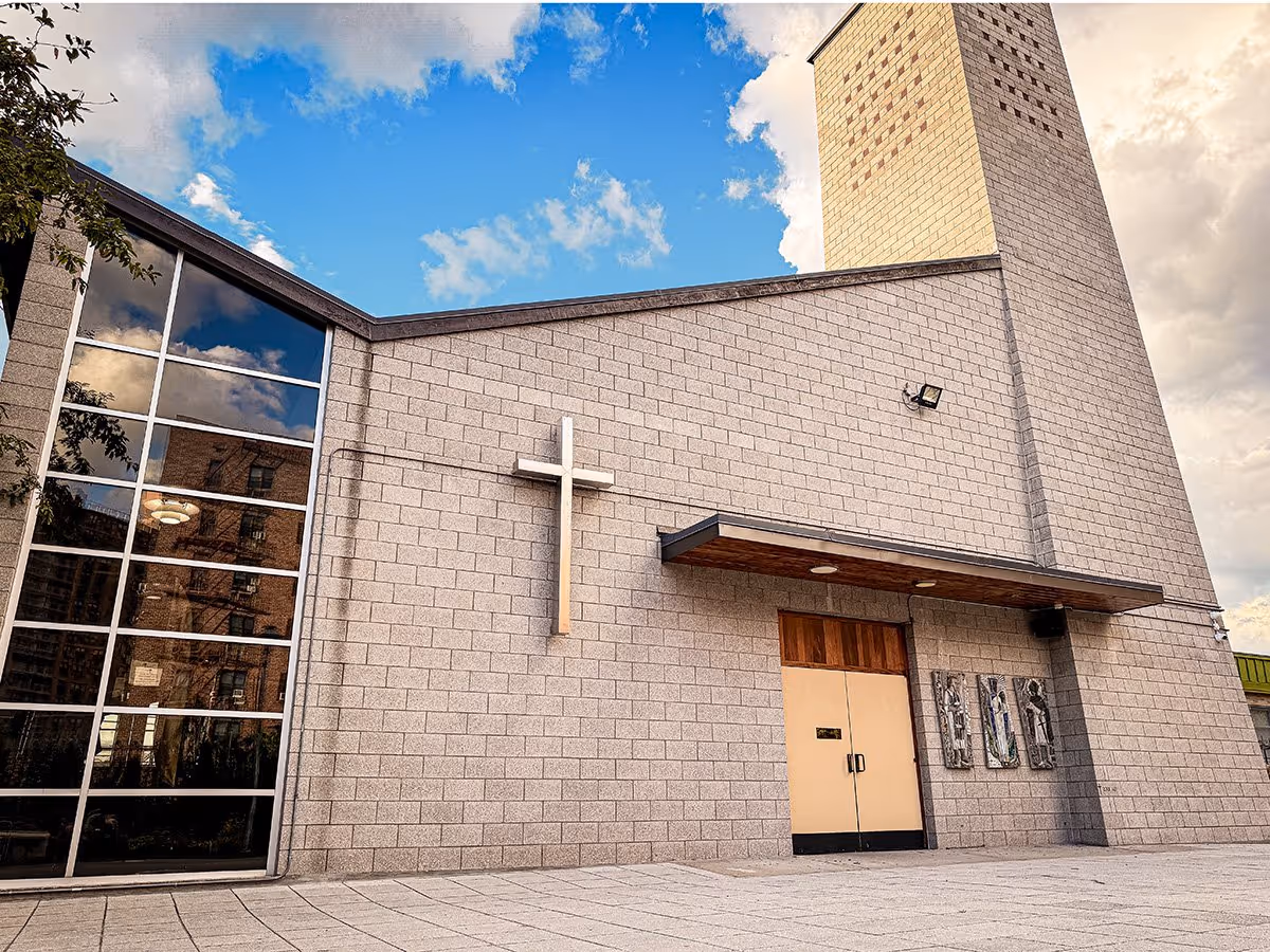 Front view of a modern church building with a cross, large windows, and double doors.