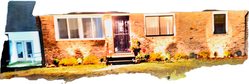 Brick senior care facility exterior at night with illuminated entrance and landscaped front yard.