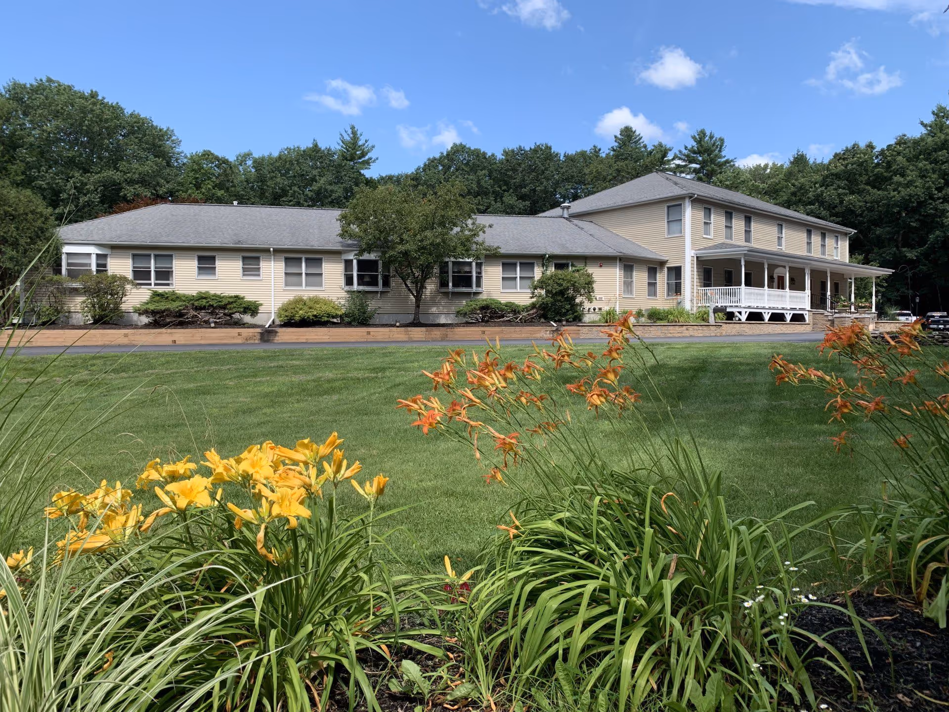 A view of the Foxden Retirement Community building surrounded by flowers and greenery.