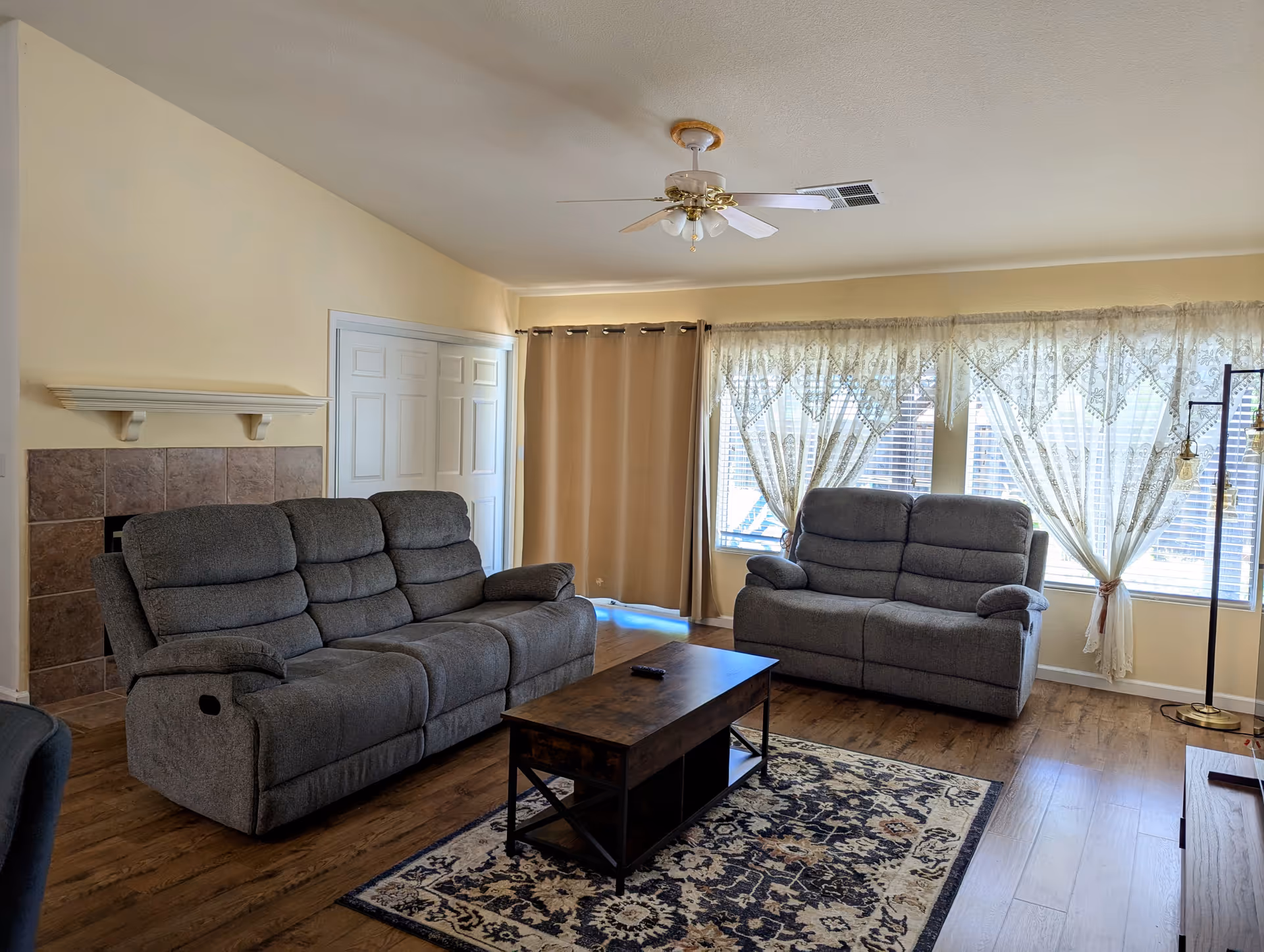 Two gray reclining sofas face a wooden coffee table in a cozy living room.