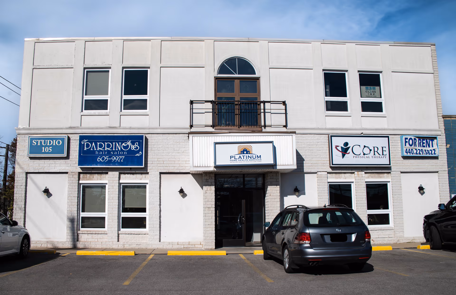 Two-story commercial building with multiple signs, including Platinum Home Health Services, and parked cars in front.