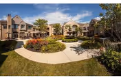 Sunny outdoor courtyard of Waltonwood Senior Community with fountain and garden paths.