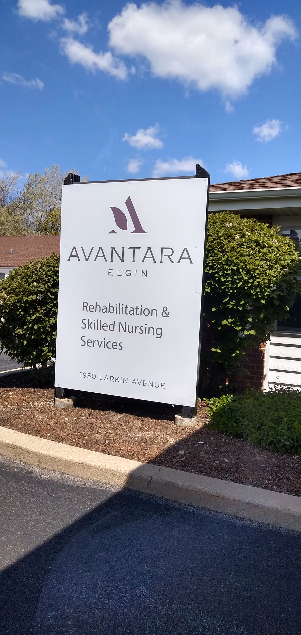 A tall white sign for Avantara Elgin Rehabilitation and Skilled Nursing Services outside a building.