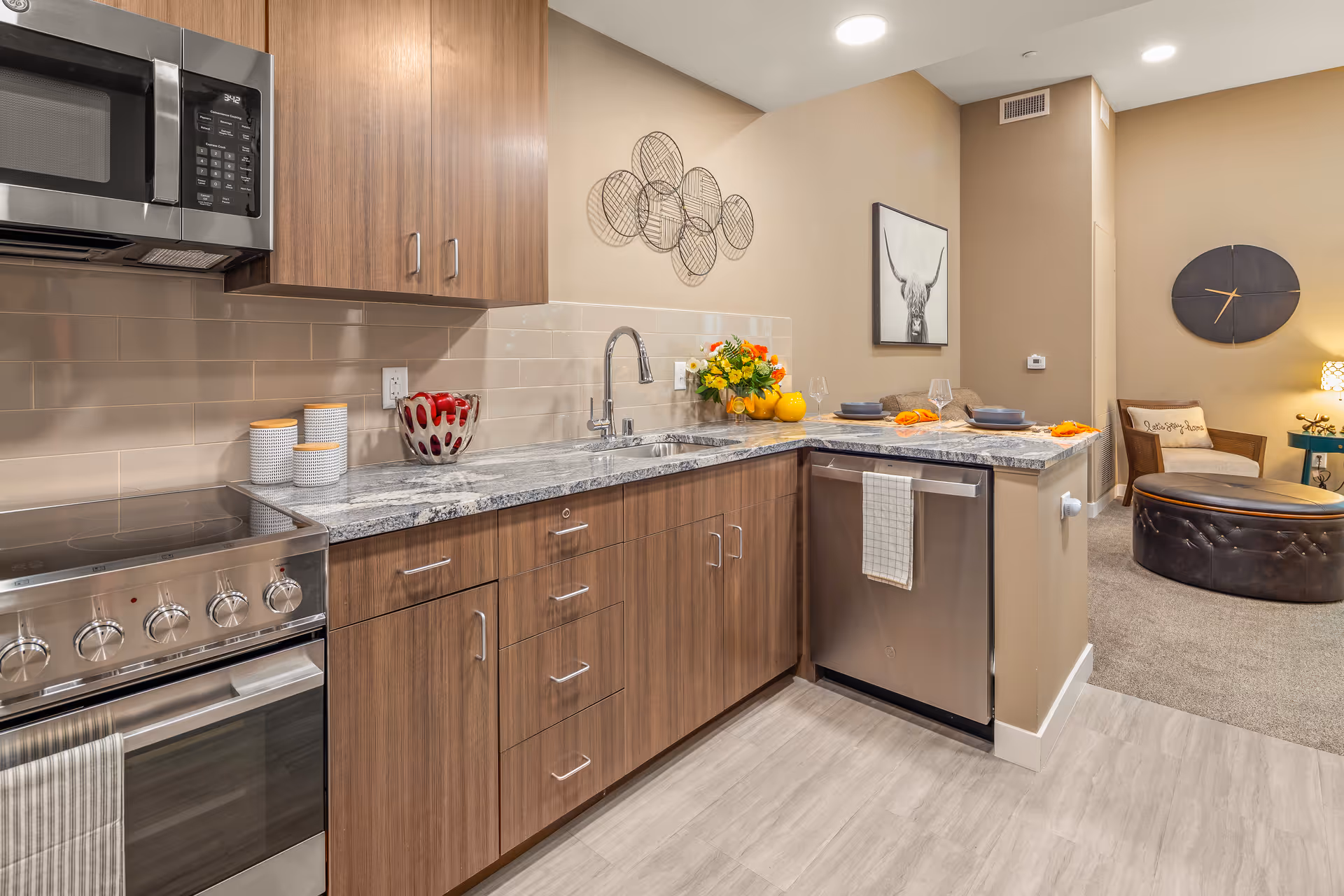 Modern kitchen with wooden cabinets, stainless steel appliances, and a connected living area.