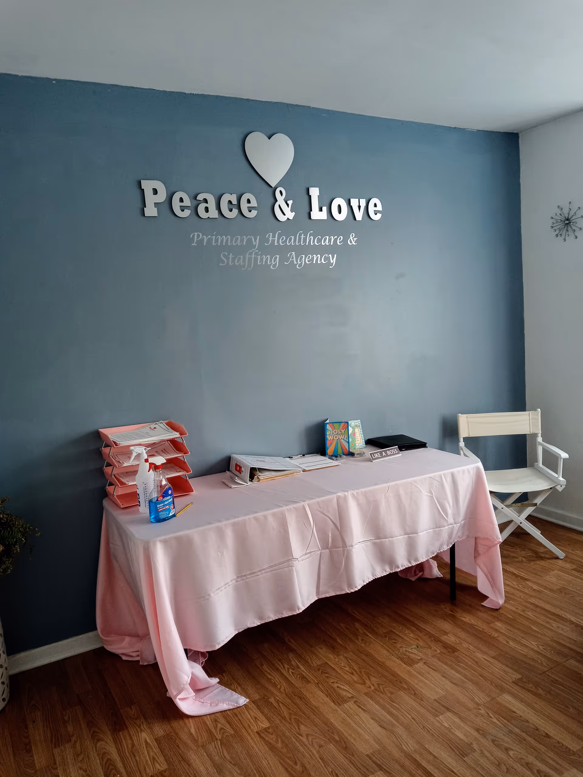 Interior reception area with teal wall sign Peace & Love and pink tablecloth.
