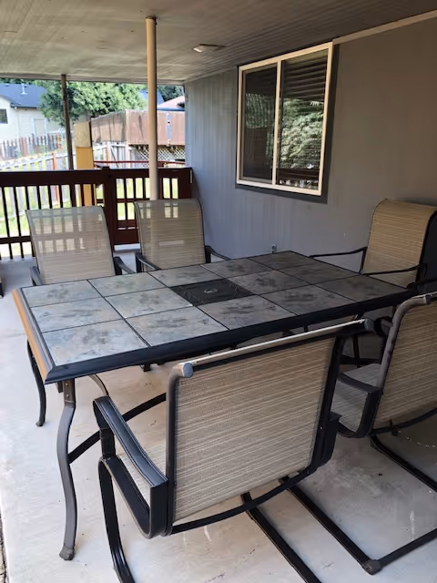Covered outdoor patio with a tile-topped table and beige chairs.