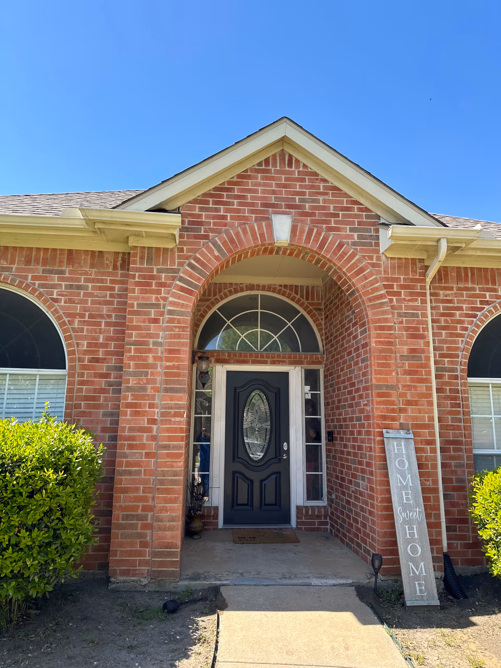 Brick senior living facility front entrance with arched doorway and Home Sweet Home sign