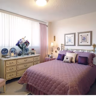 Cozy bedroom in a senior living community with a purple quilted bedspread.