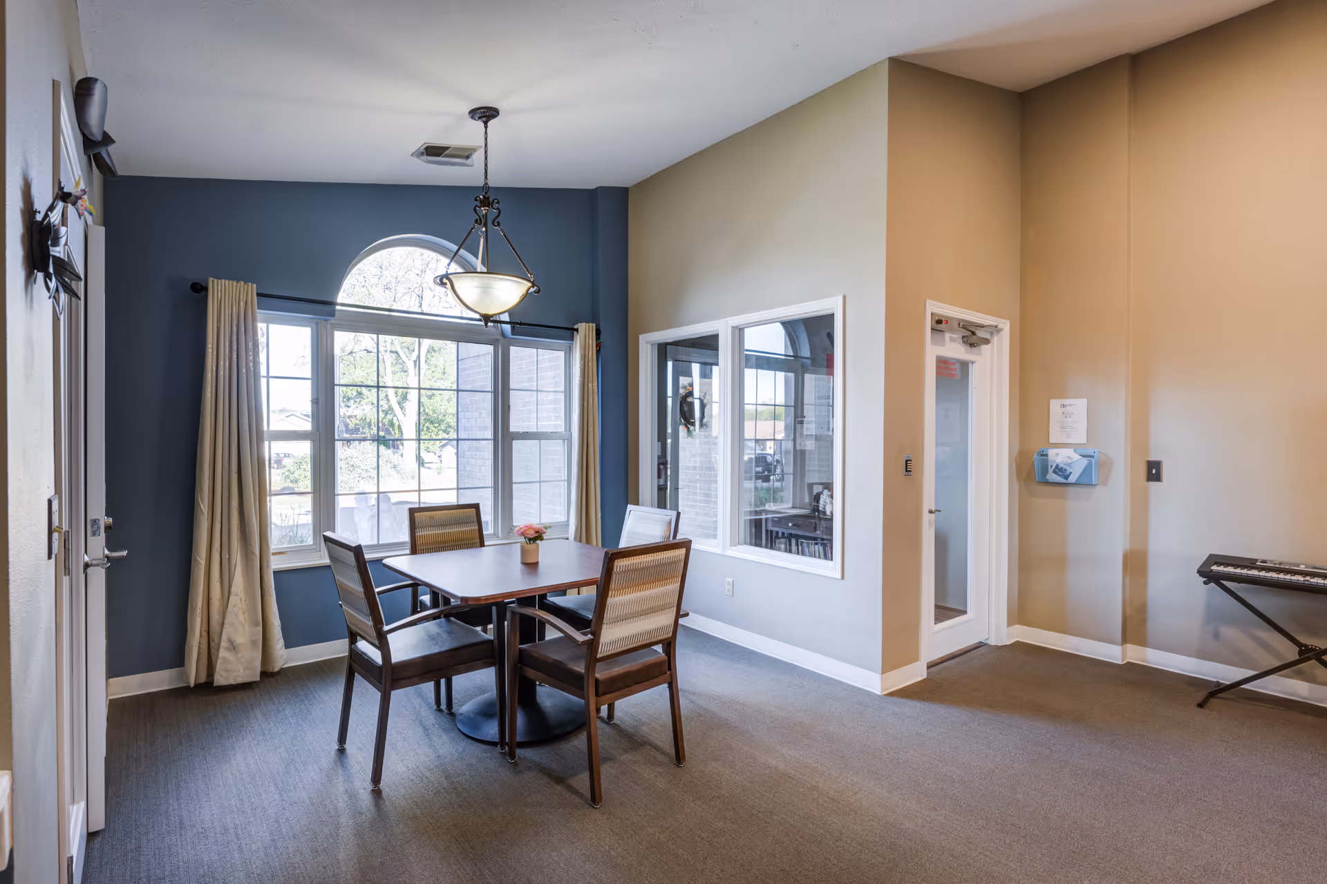 Dining area at Dimensions Living Monroe with round table, four chairs, and a blue accent wall.