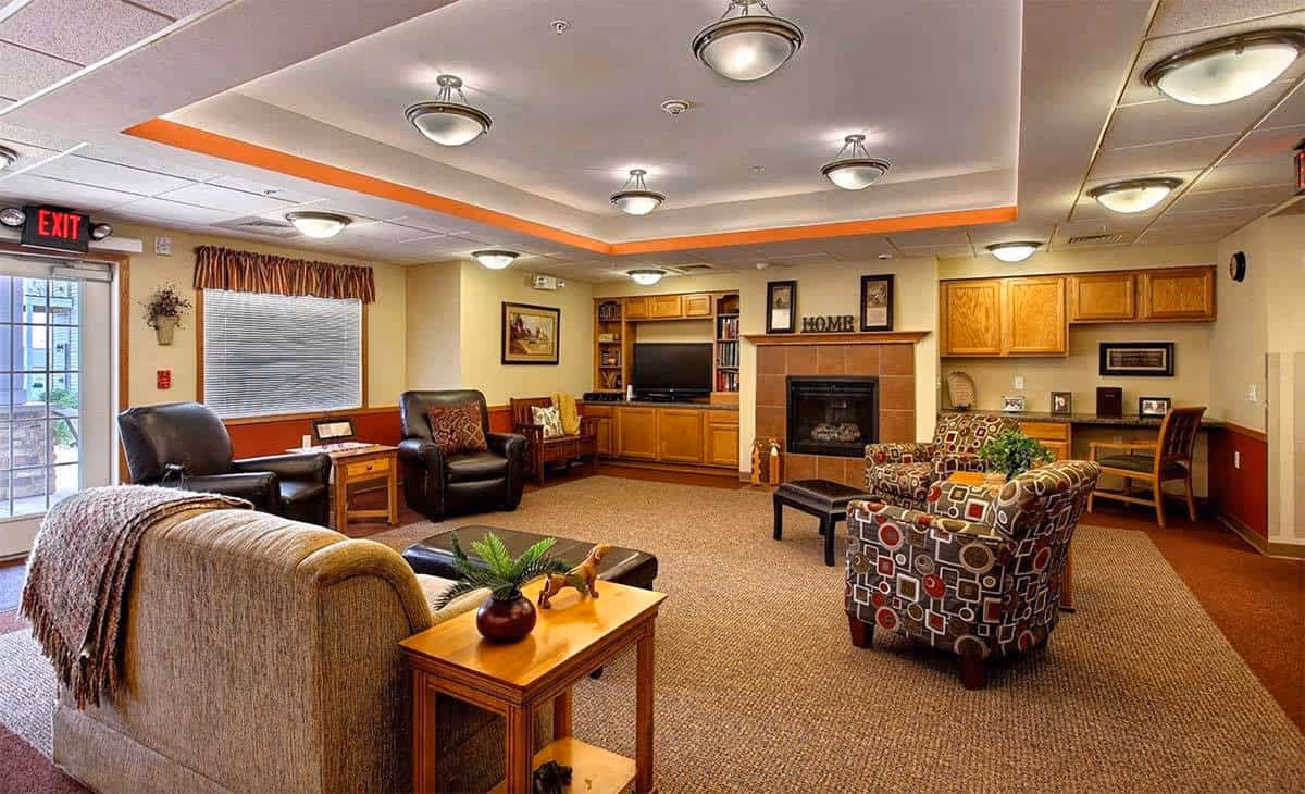 Common living room with couches, chairs, fireplace, and built-in wooden cabinets.