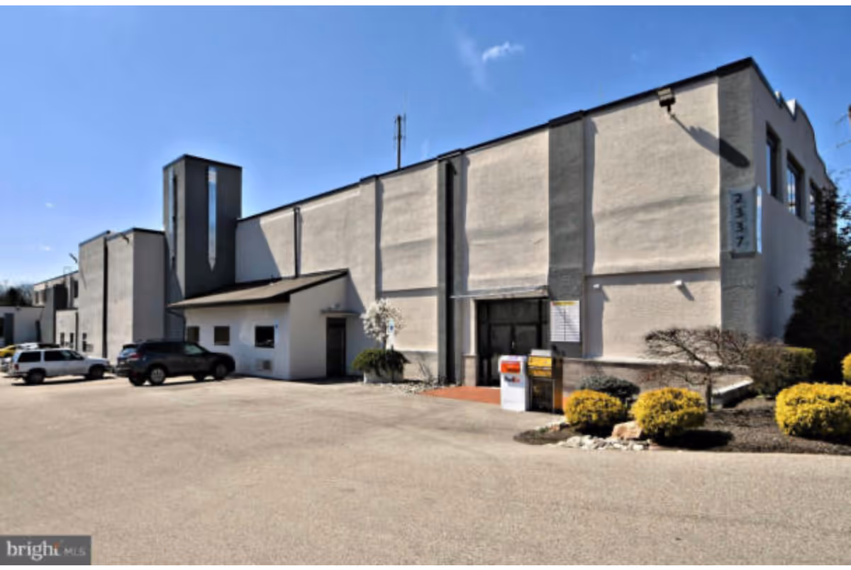 Exterior view of a gray, boxy senior care building with a parking lot.