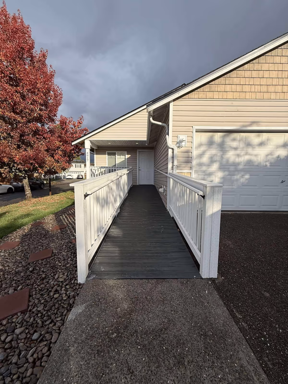 Exterior view of a senior living facility entrance with a ramp and surrounding landscaping.