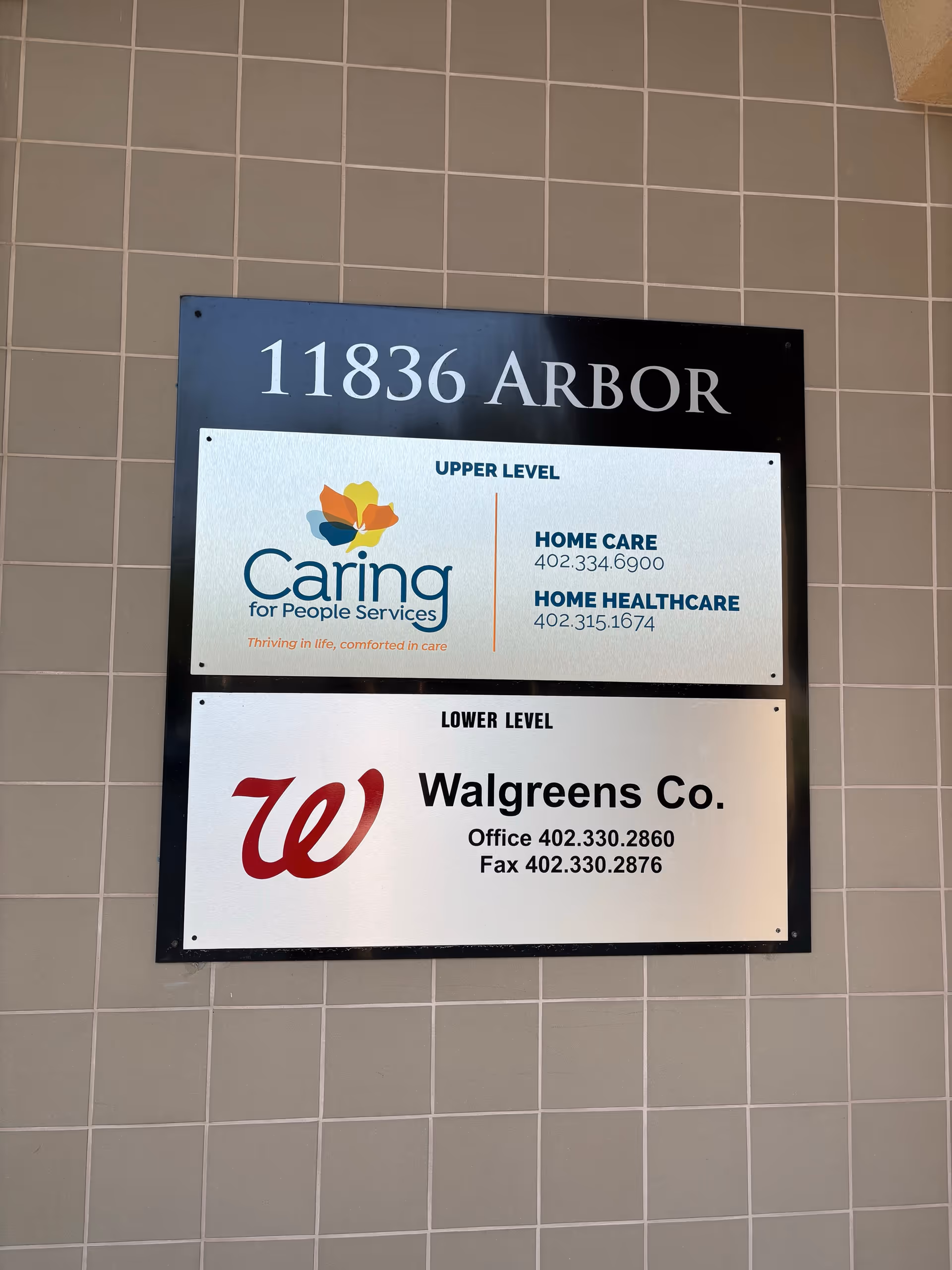 Signboard on tiled wall listing Caring for People Services and Walgreens at 11836 Arbor