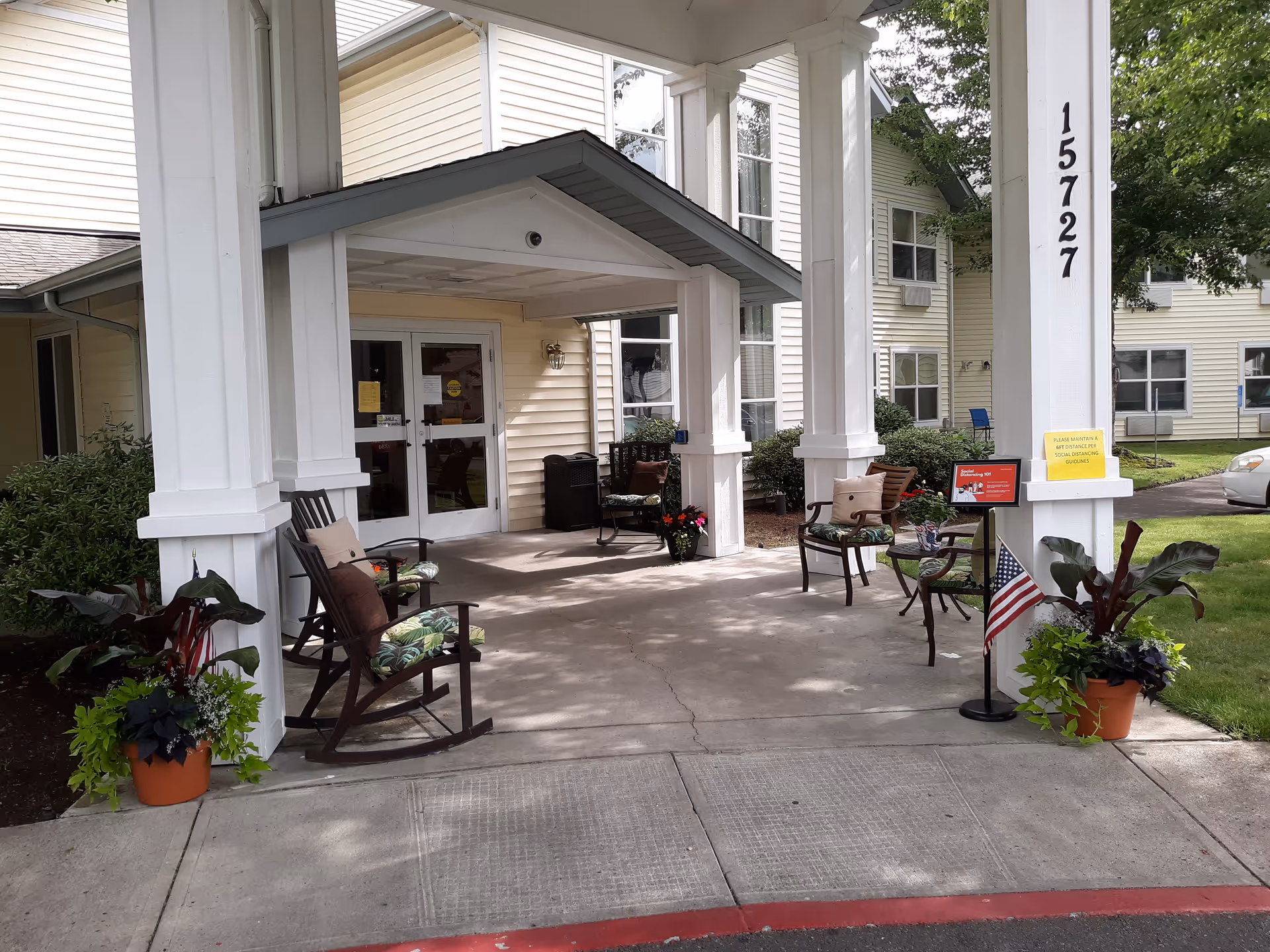Covered front entry with rocking chairs, potted plants, and an American flag at Diamond Care AFC.