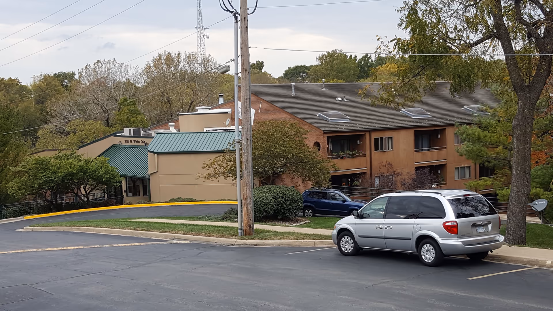 Exterior of Rosewood Health and Rehab with a parked minivan and trees.