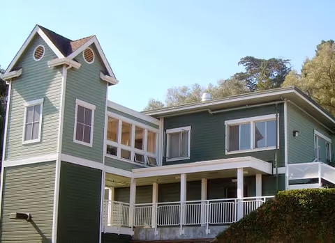 Exterior view of a green, two-story senior living building with balconies.