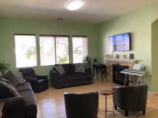 Cozy living room at Bella Vita Care Home with sofas, fireplace, and mounted TV.
