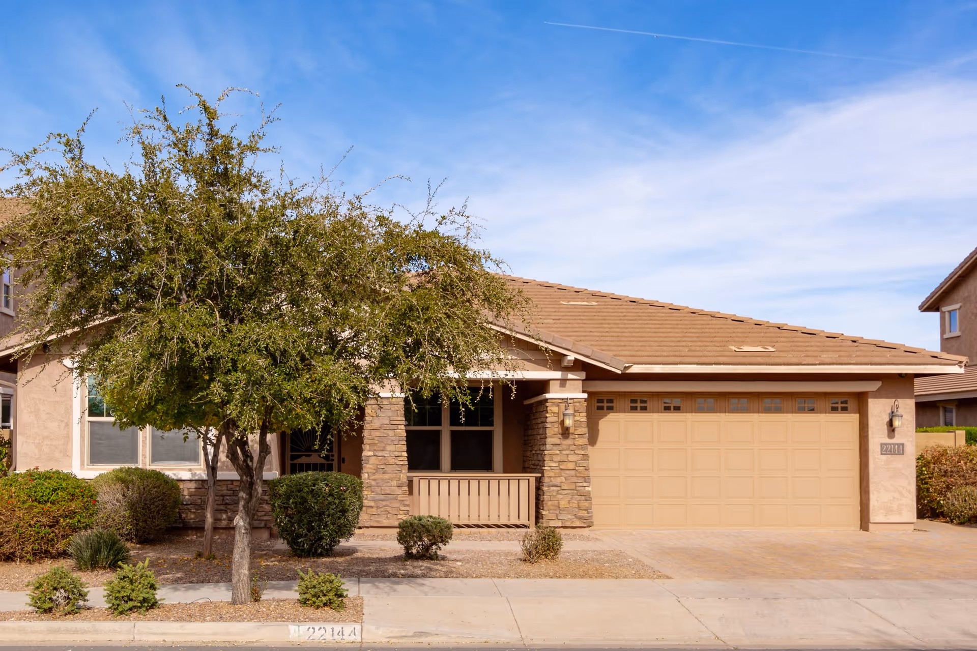 Single-story beige assisted living facility exterior with stone pillars, small front porch, and a two-car garage.