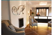 Lobby reception area with chairs, a fireplace, and a receptionist at the desk.