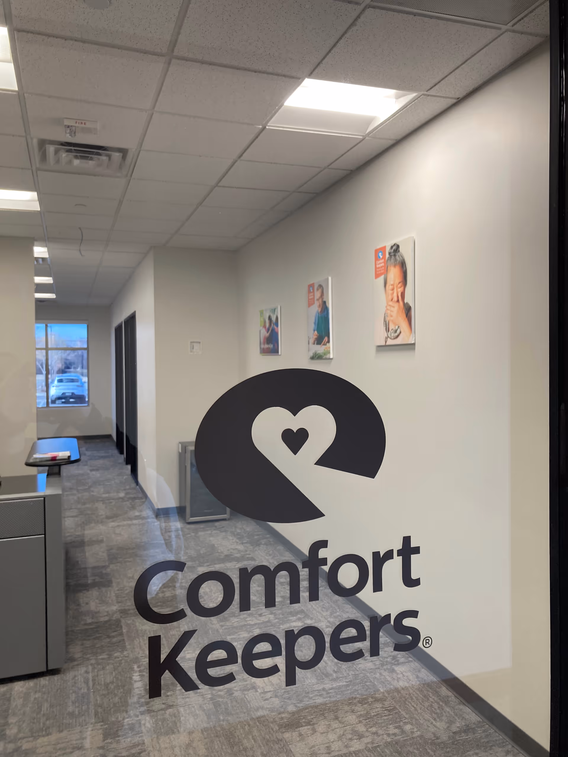 Indoor hallway with a large Comfort Keepers logo on a glass panel.