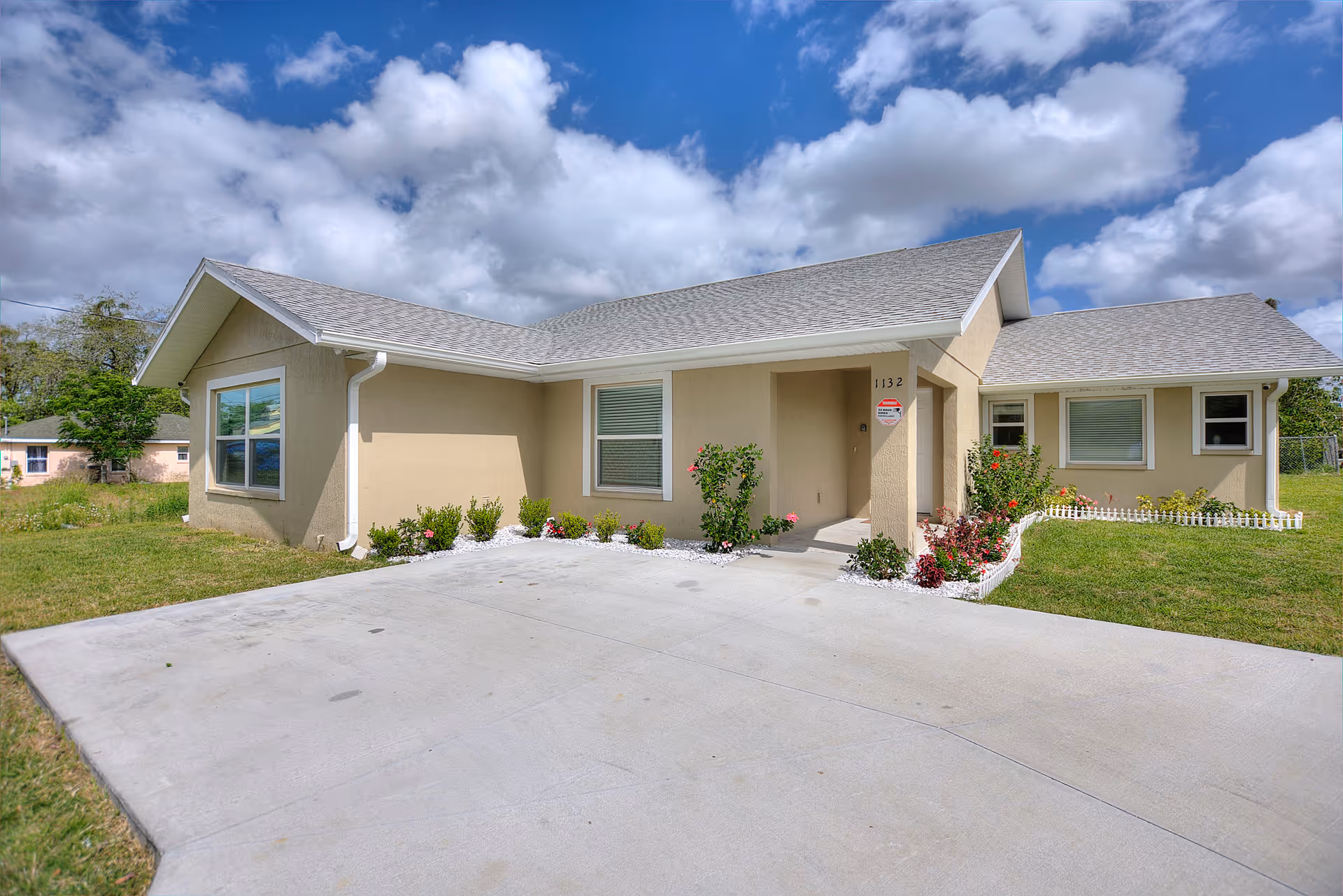 Single-story beige senior living facility exterior with a wide driveway and landscaped entrance.