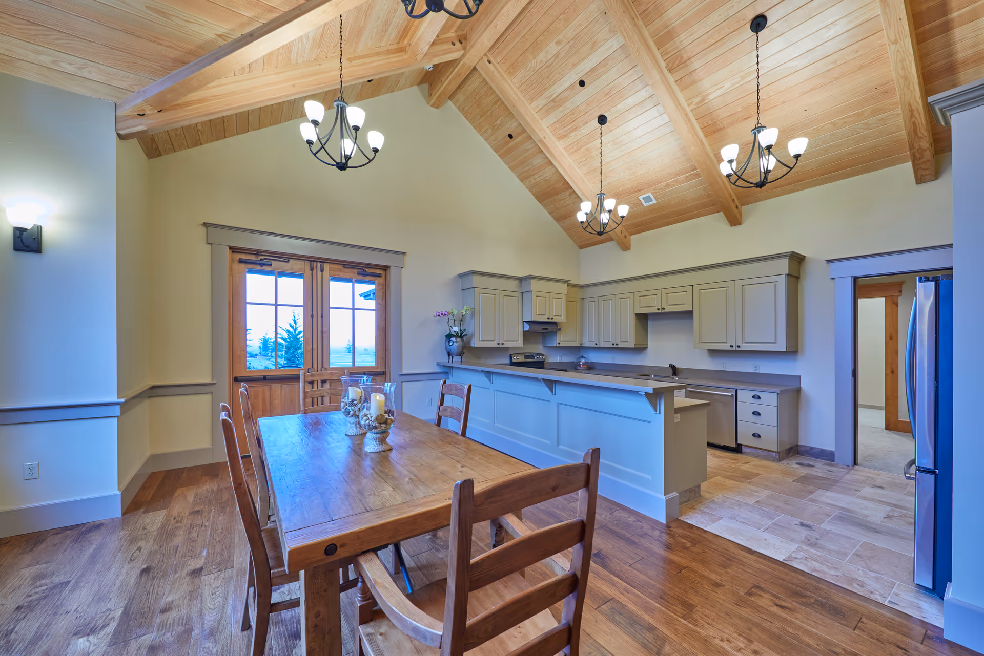 Bright open kitchen with an island, wooden cabinets, and a nearby wooden dining table.