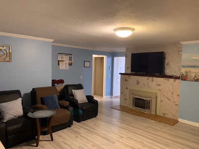 Cozy common living room with recliners, a fireplace, and a wall-mounted TV.
