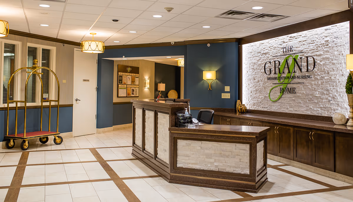 Reception desk in a modern interior lobby with stone wall and luggage cart.