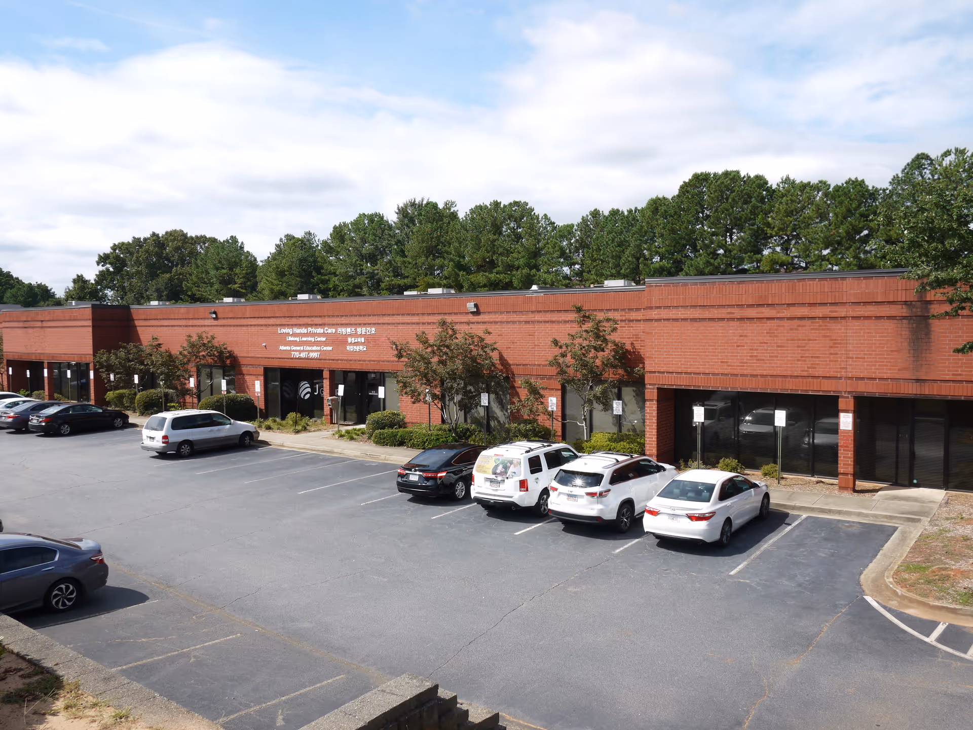 Exterior view of Loving Hands Private Care building with parked cars in front.