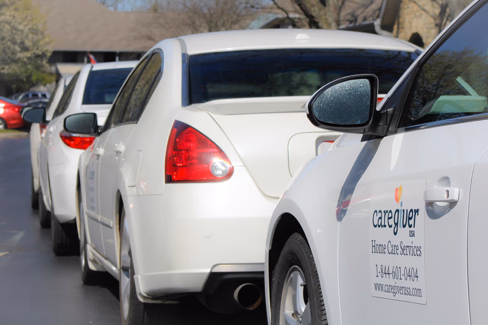 Line of white cars parked in a lot with a visible Caregiver USA logo.