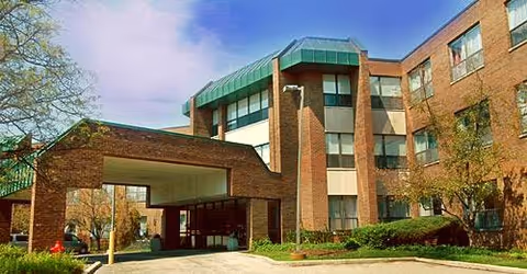 Exterior view of a brick senior care center with a covered entrance.