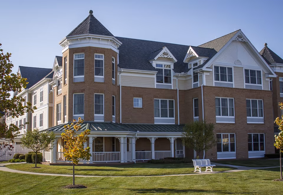 Exterior view of a brick senior living facility with a front porch and lawn.