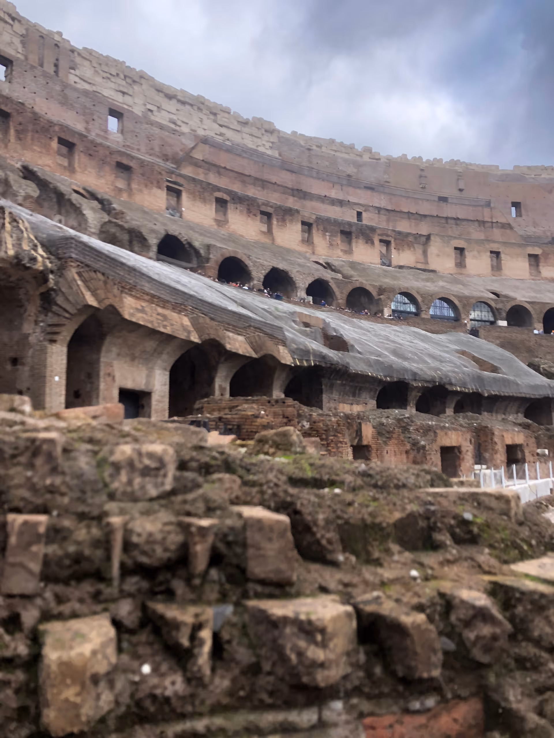 Ancient stone amphitheater ruins with arches beneath a cloudy sky.