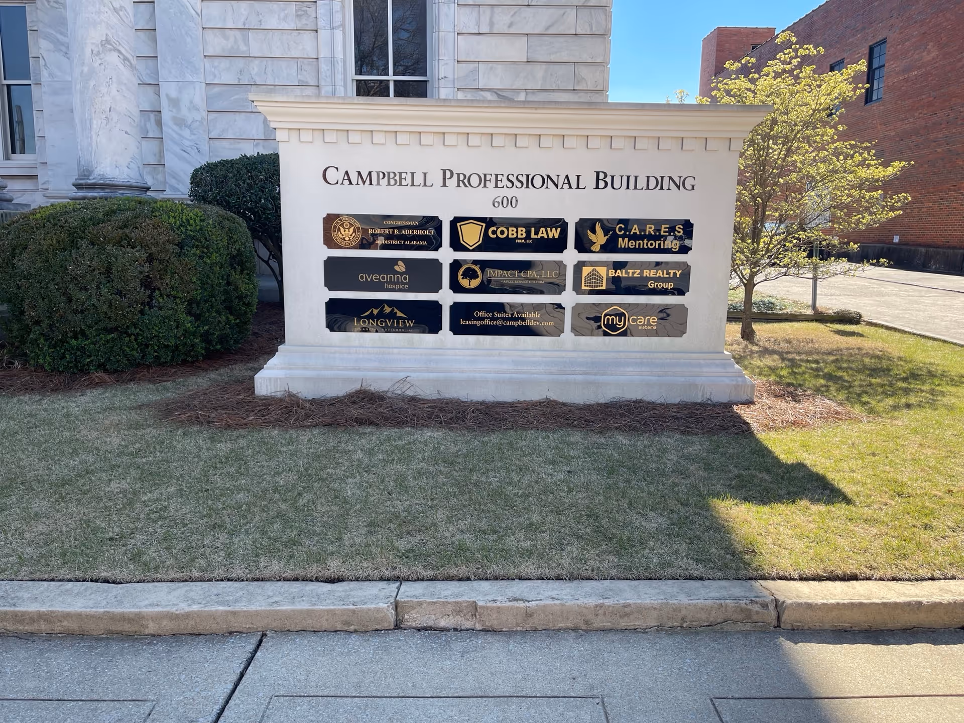 Stone signboard with multiple tenant plaques in front of Campbell Professional Building.