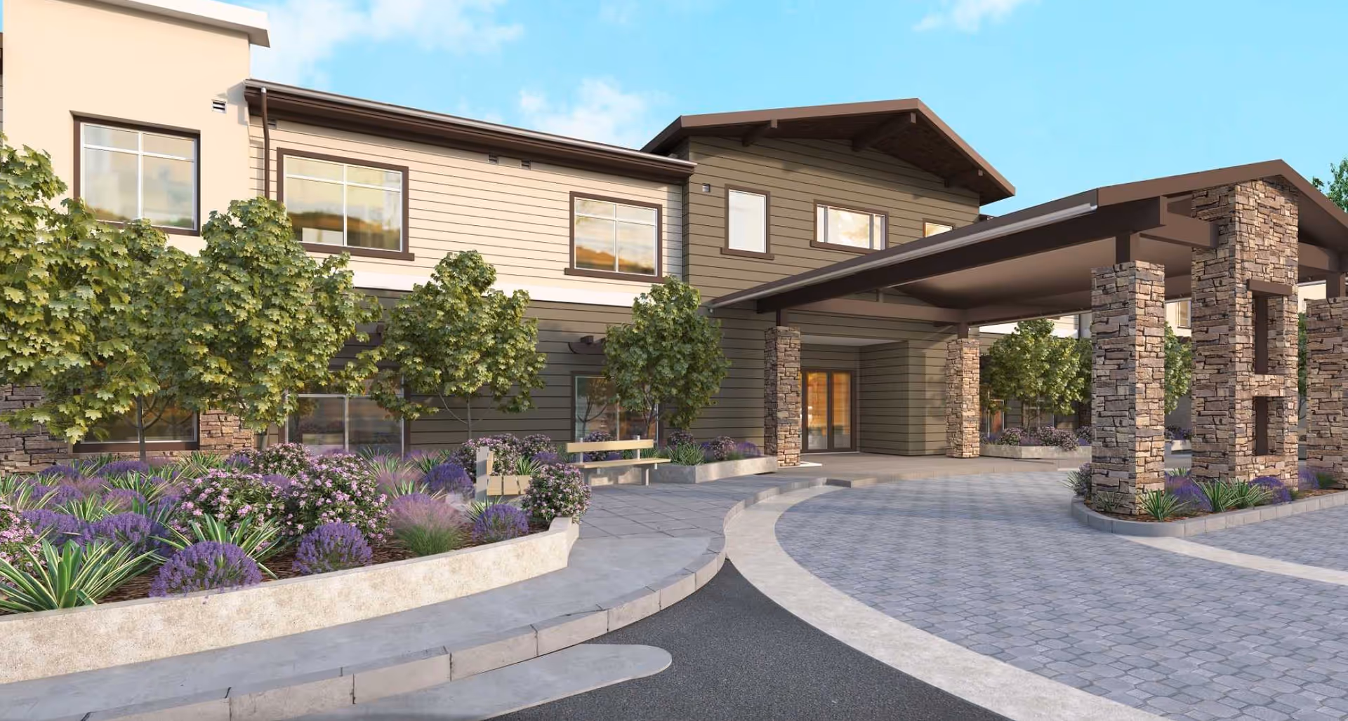 Exterior view of Peninsula Pointe facility showing a covered entrance with stone pillars, landscaped garden beds with green shrubs and purple flowers, and a paved driveway under a blue sky.