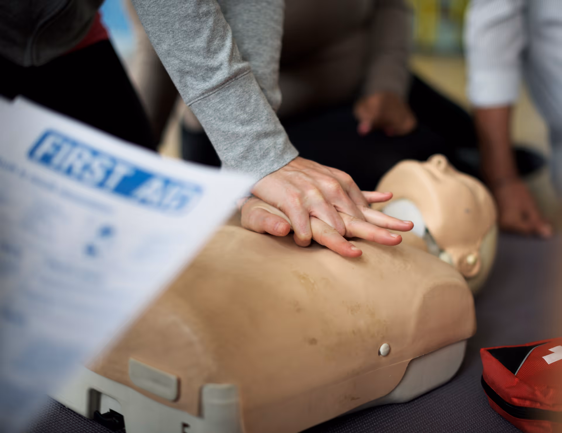 Hands perform CPR on a medical training mannequin indoors
