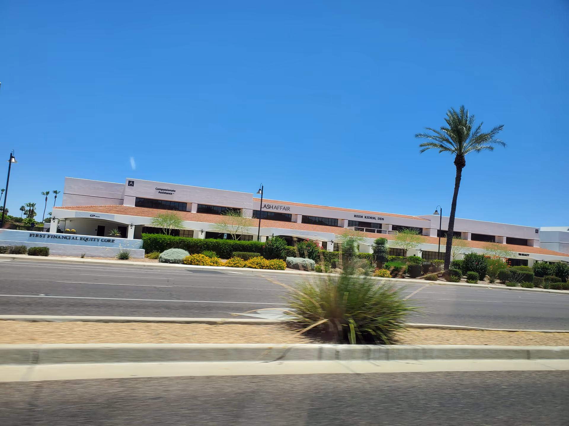Exterior view of a low-rise building labeled Compassionate Assistance with palm trees and desert landscaping