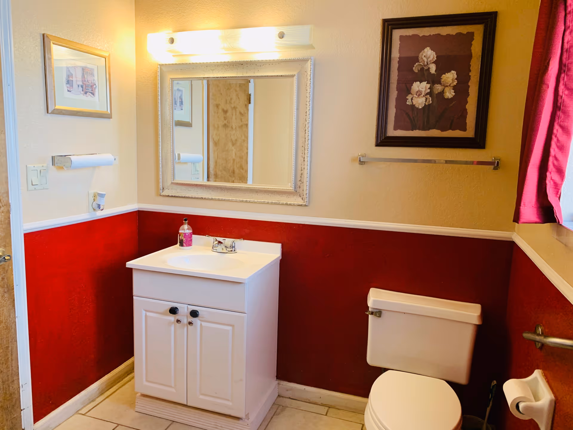 Small bathroom with a white vanity, mirror, toilet, and burgundy wainscoted walls.