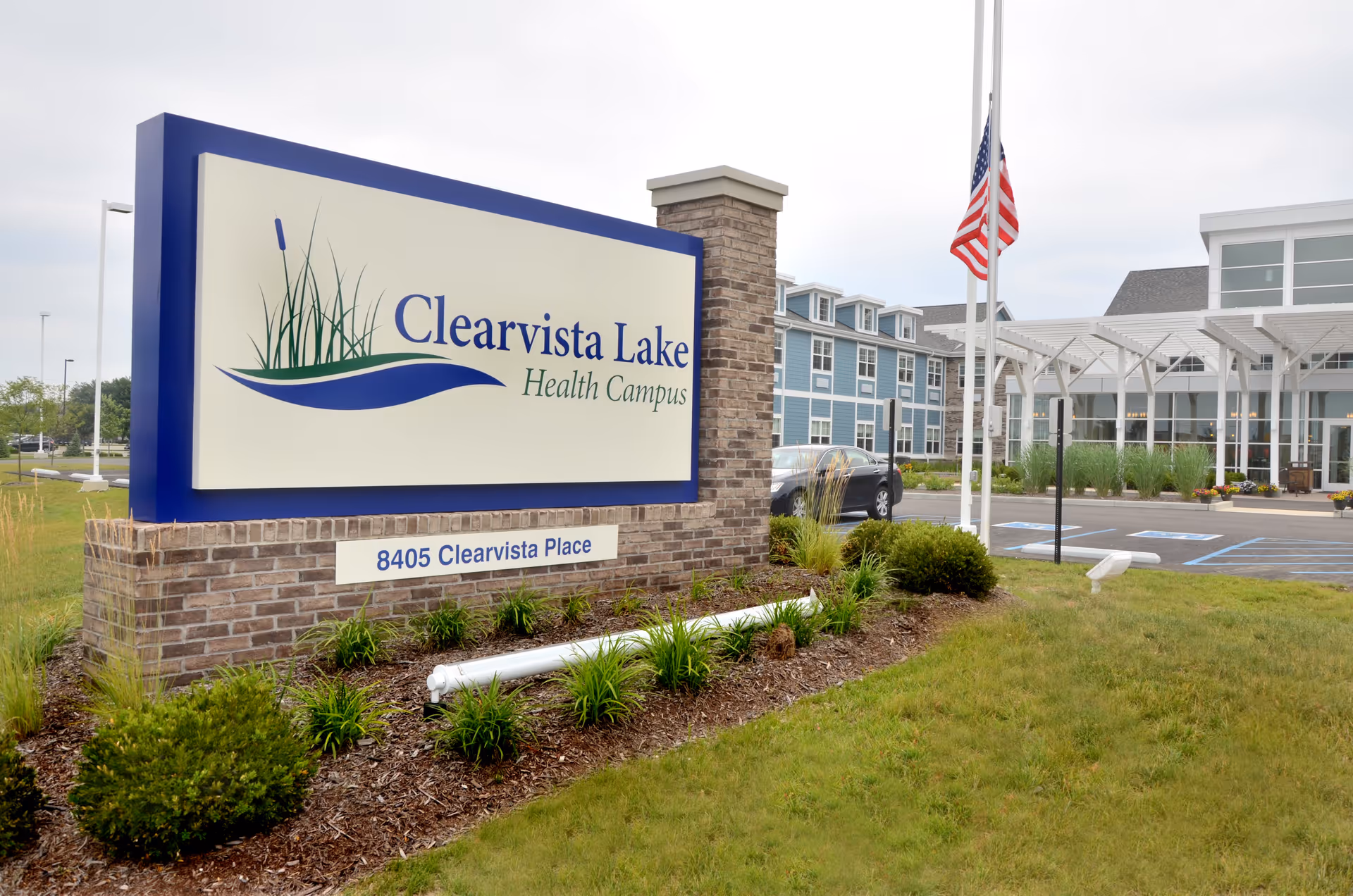 Front view of Clearvista Lake Health Campus sign, brick base, and building entrance with American flag