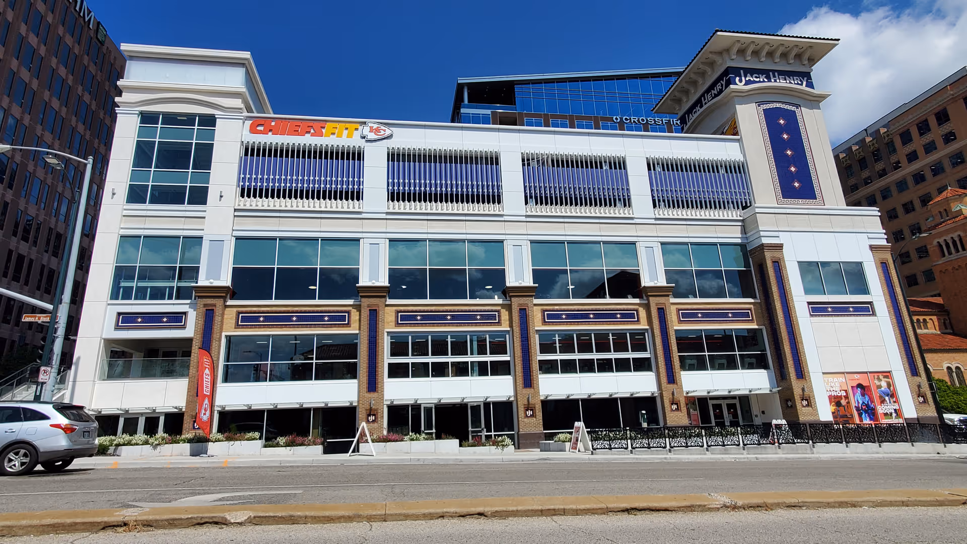 Modern multi-story building with large glass windows, decorative pillars, and street-level storefronts.