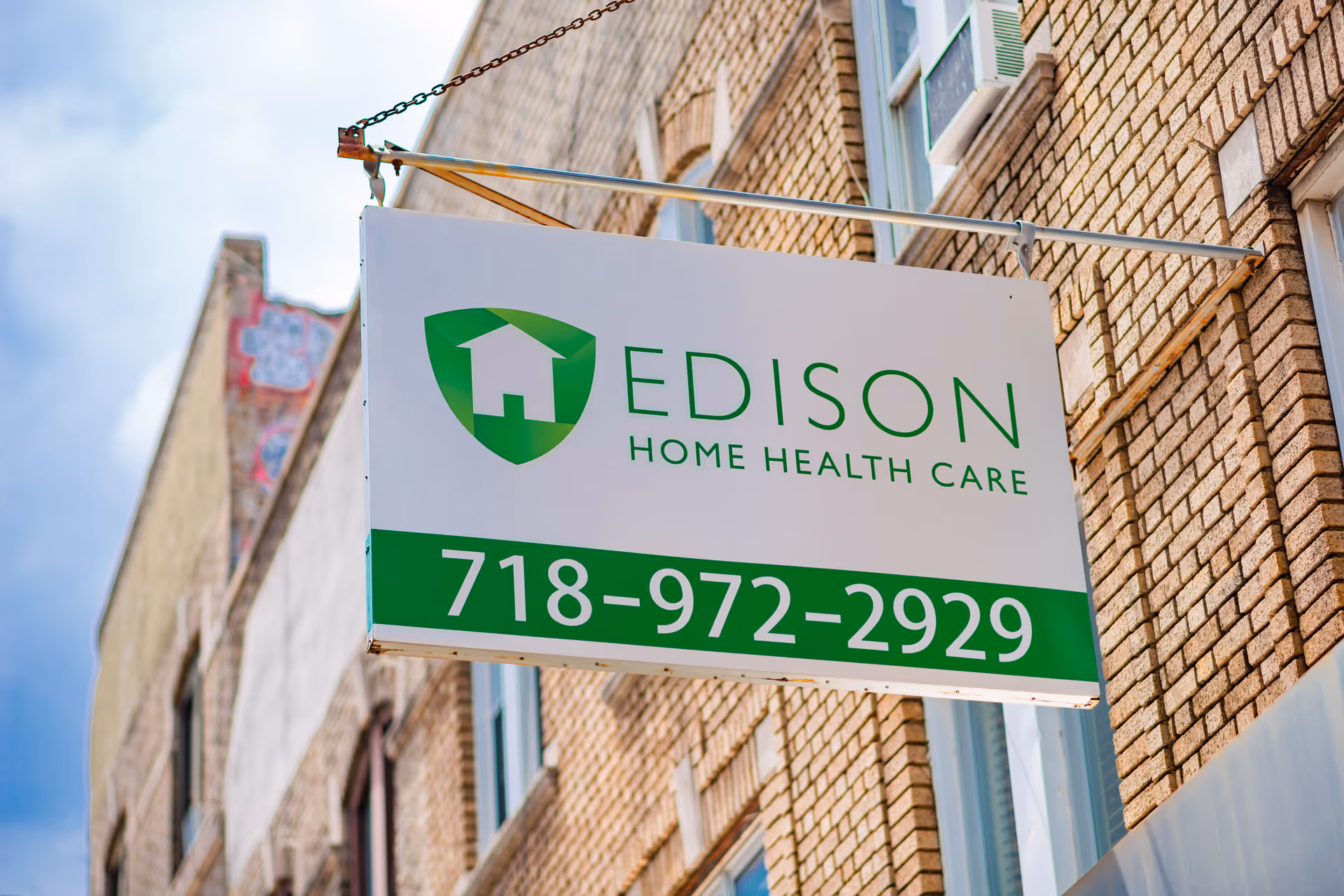 A hanging Edison Home Health Care sign on a brick building exterior.