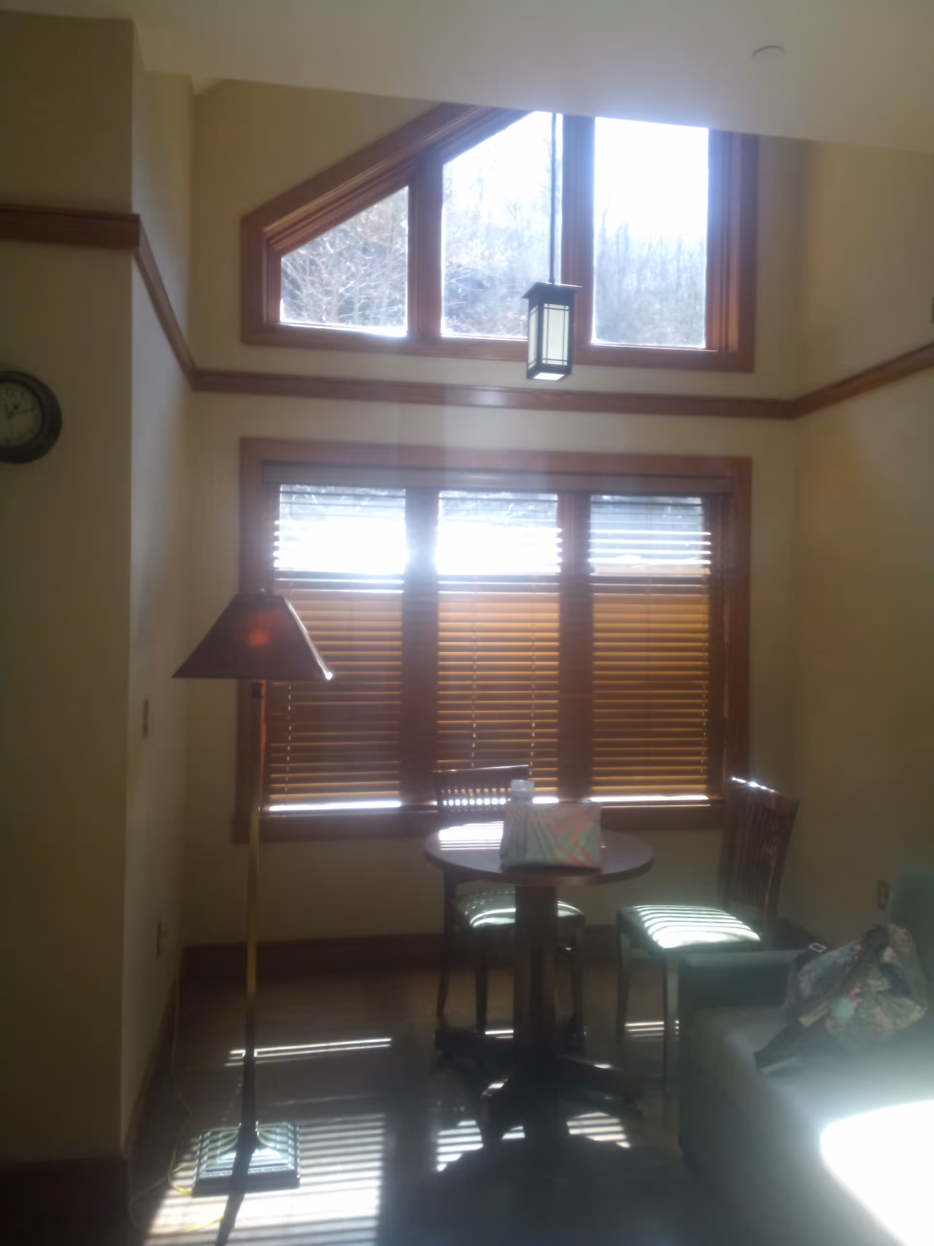 A cozy dining nook with round table, two chairs, blinds, and warm wood trim.