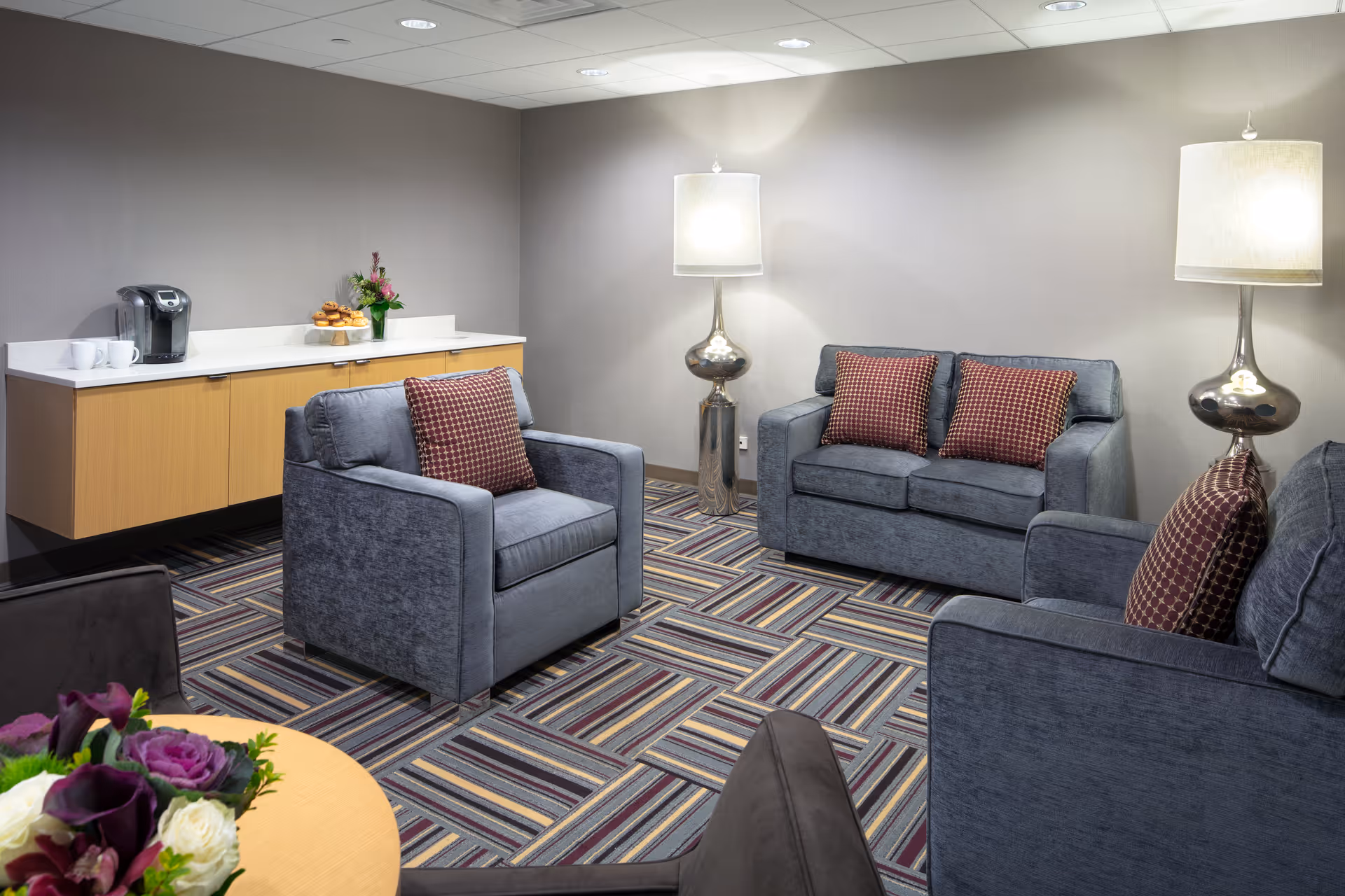 Cozy gray lounge area with sofas, lamps, and a refreshment counter.